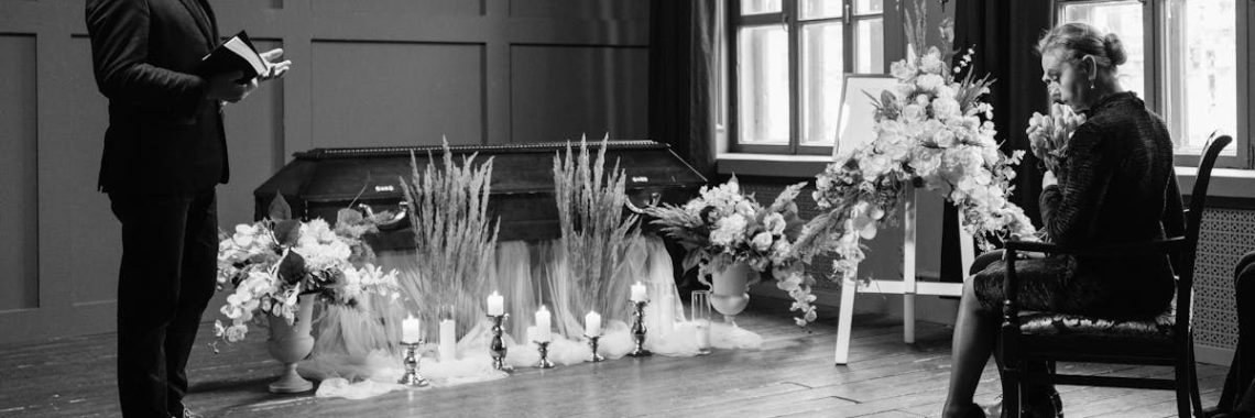 A somber funeral scene in grayscale showing a pastor and woman mourning.